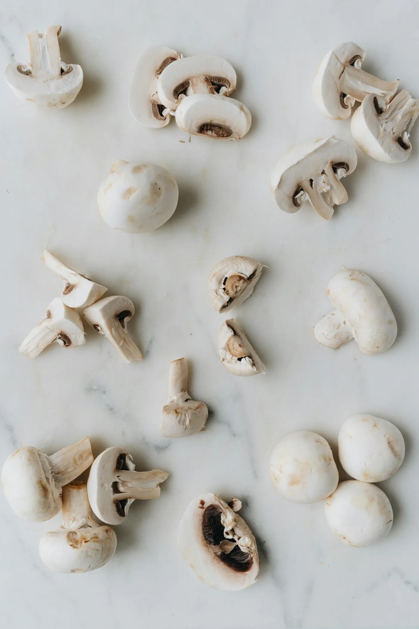 Sliced mushrooms laid out on a pale marble surface